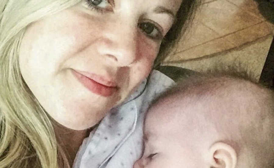 Mother who was diagnosed with cancer smiles in selfie with newborn sleeping on her shoulder