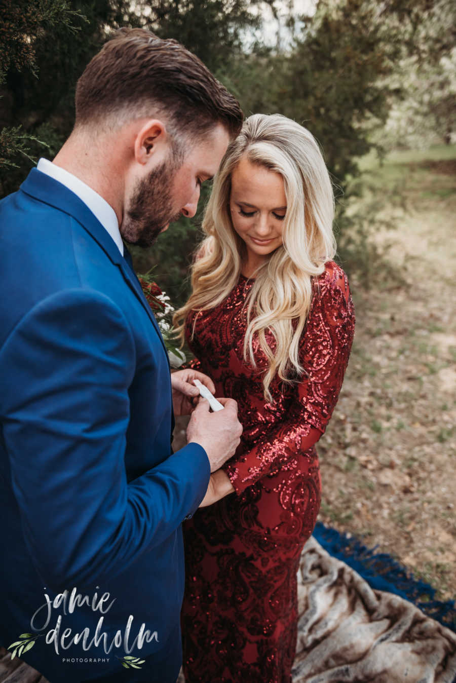 Husband and wife look down at pregnancy test husband holds in his hands