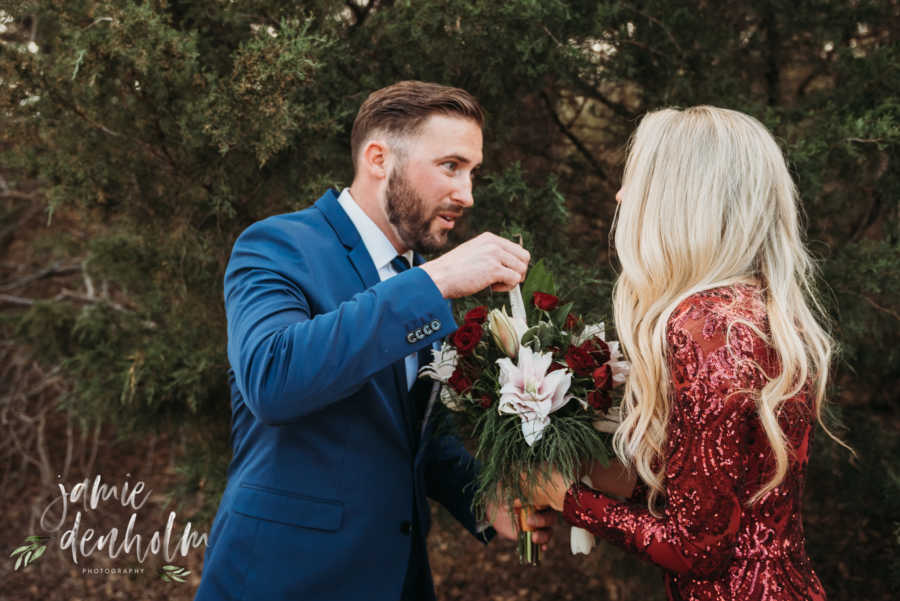 Husband stares at wife as he pulls pregnancy test of of bouquet his wife is holding