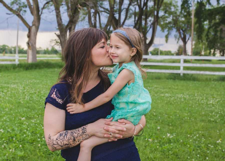 Mother holds and kisses youngest daughter on the cheek who she has sworn in front of