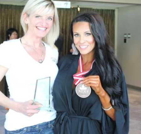 Fitness competitor who now had POTS Disease holds up medal around her neck besides another competitor