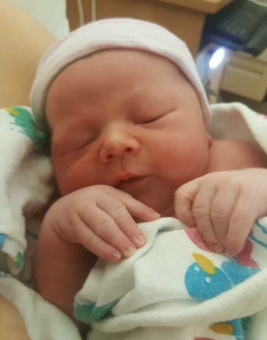 Close up of newborn boy asleep swaddled in blanket with hat on