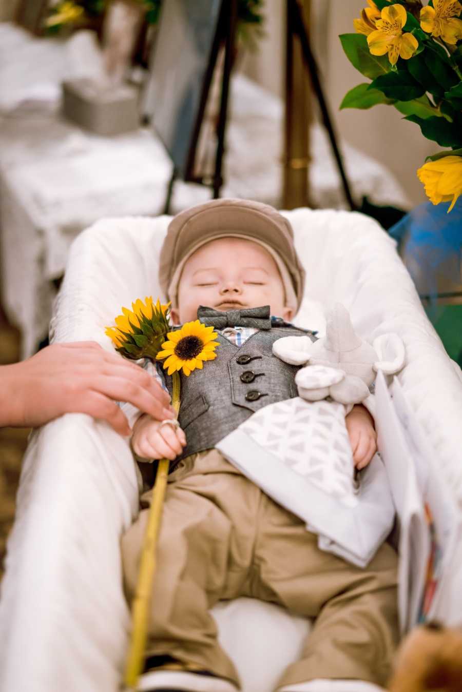 Deceased 8 month laying in coffin holding onto blanket and sunflower