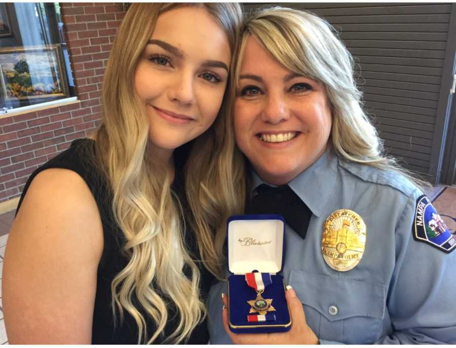 Widow mother stands in police uniform holding medal beside daughter