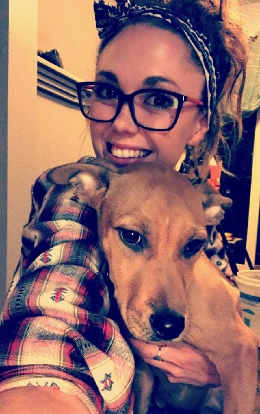 Woman smiles in selfie holding her dog she adopted