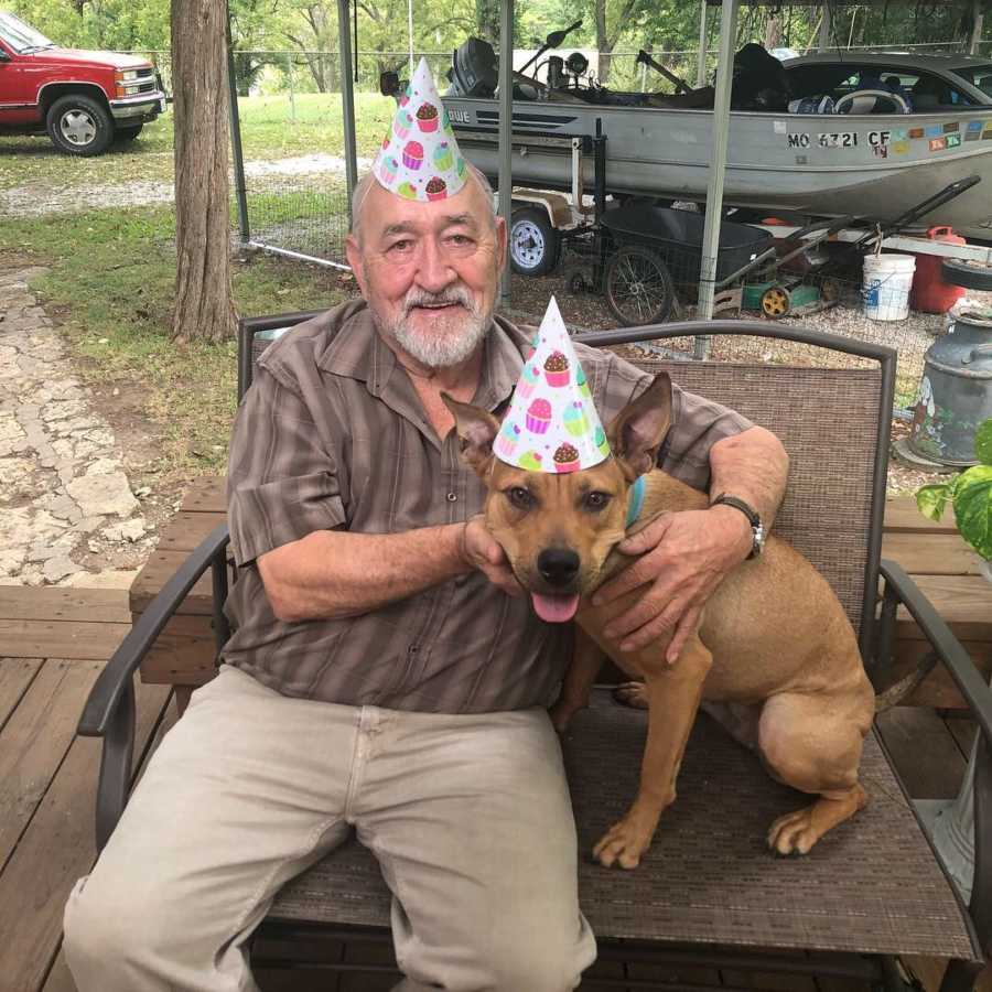 80 year old man wearing party hat sitting on porch with adopted dog beside him in same party hat