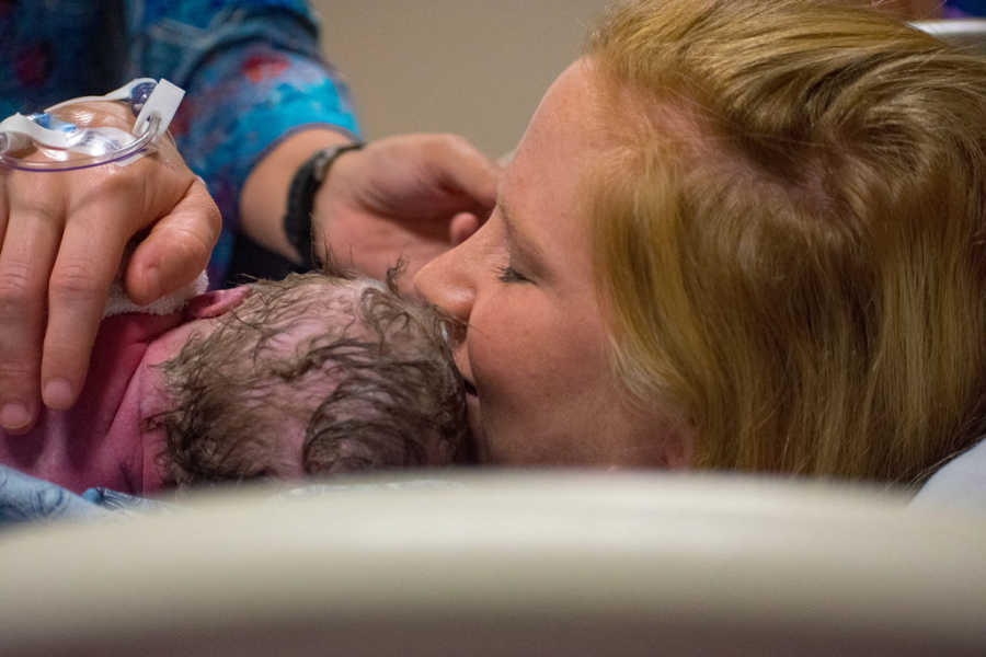 Woman holds newborn tight to her chest after she gave birth