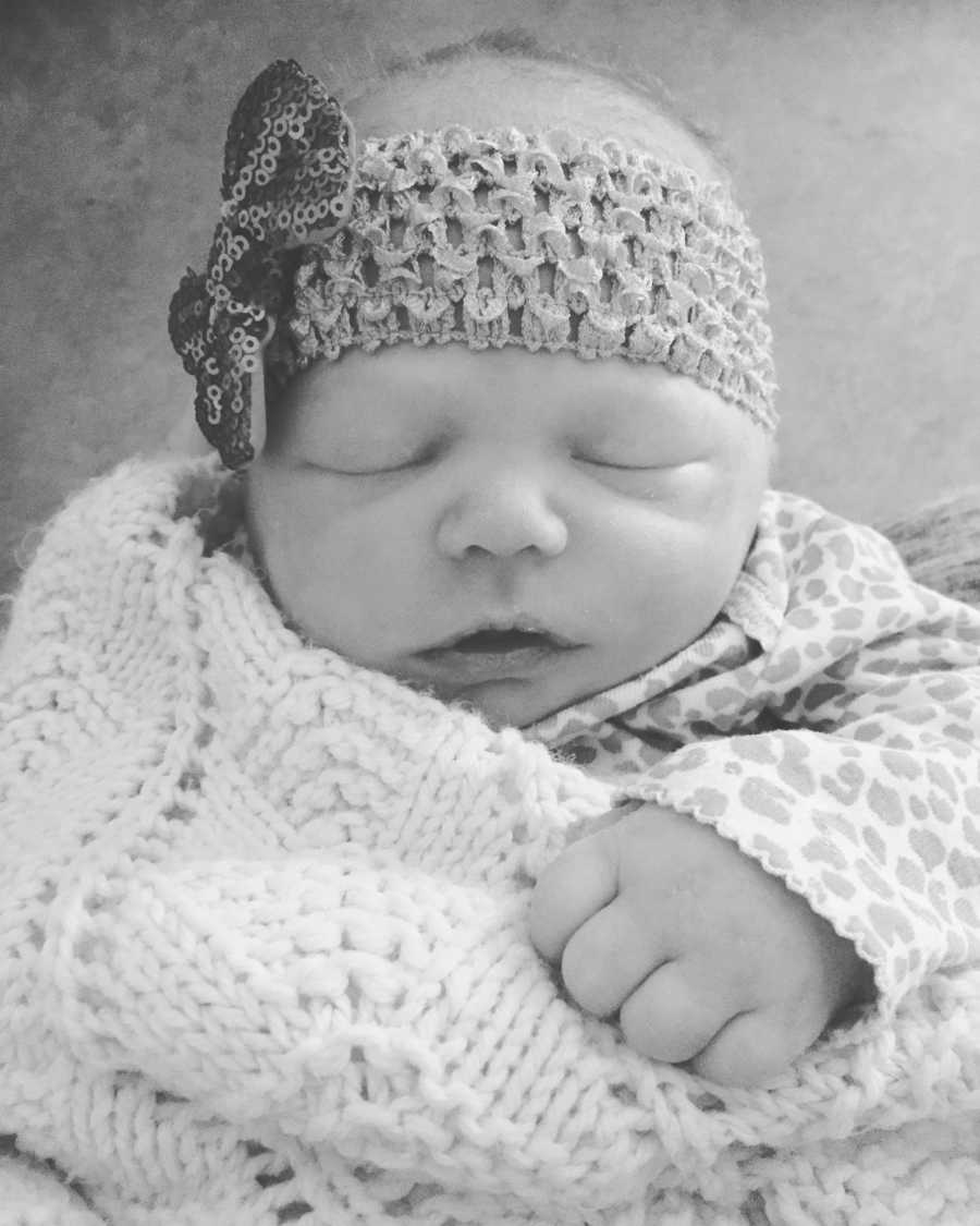 Newborn who didn't live long sleeps in blanket with headband on her head 