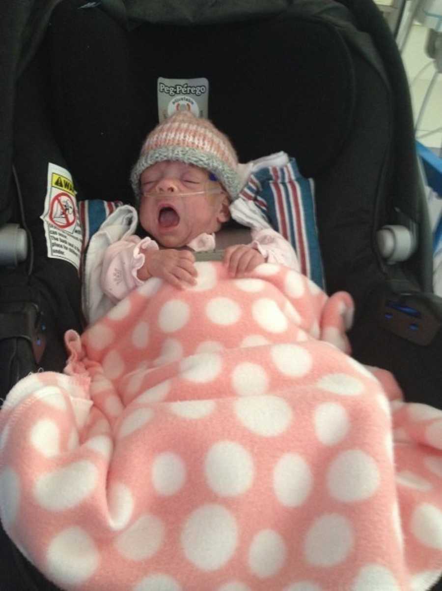 Preemie baby sleeping in stroller with pink blanket on her who finally gets to go home