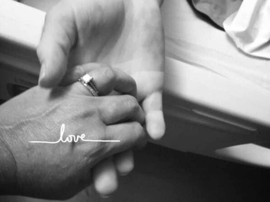 Close up of wife holding husband's hand who died from pancreatic cancer
