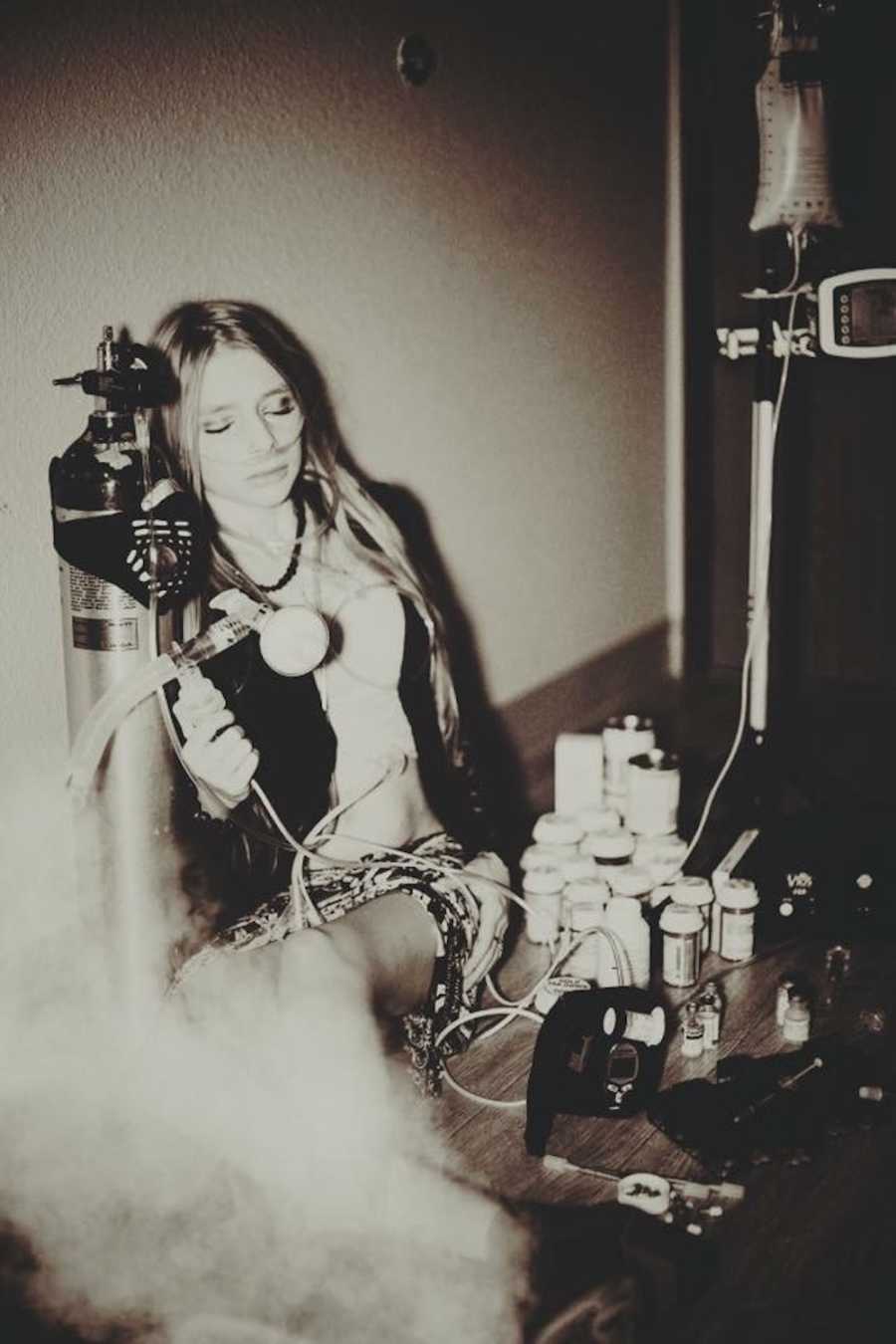 Woman with Cystic Fibrosis sitting on floor next to her oxygen tank and bottles of pills