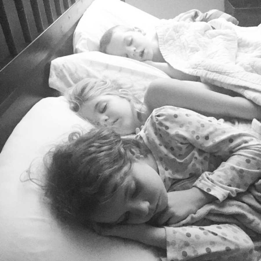 Three children sleeping in single parent's bed