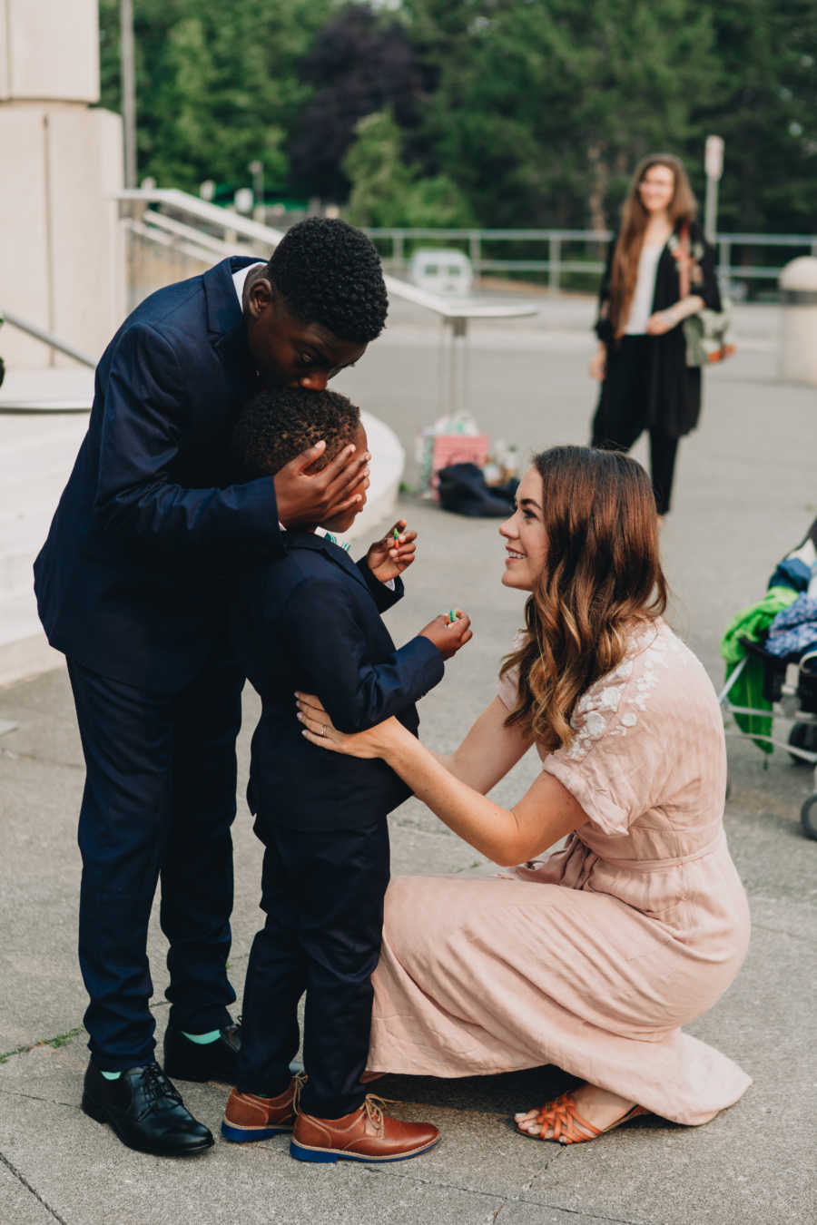 Woman squats in front of her adopted son whose biological brother kisses him on his head