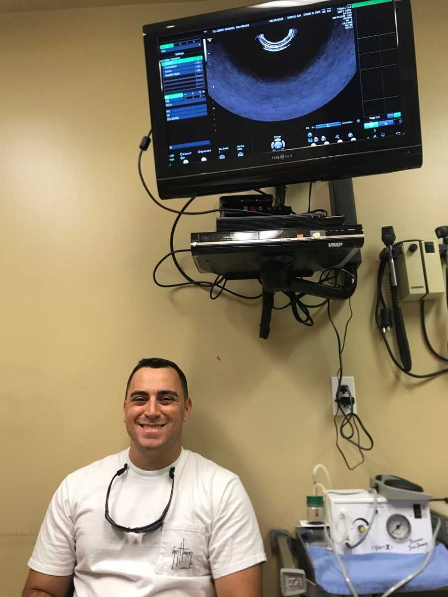 Man whose wife struggles with fertility sits in fertility clinic room under monitor