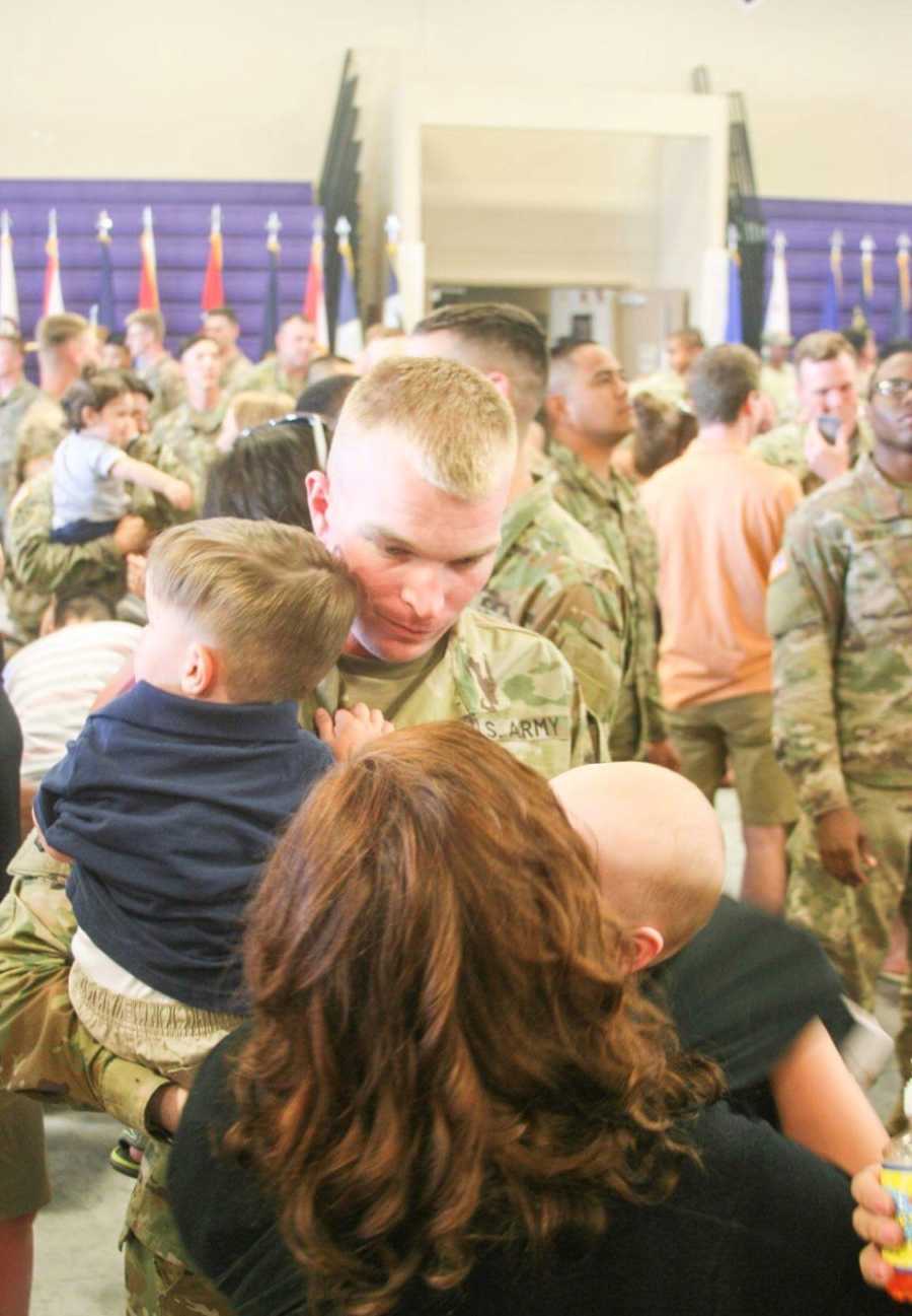 Husband who is about to be deployed holds adopted son beside wife and daughter