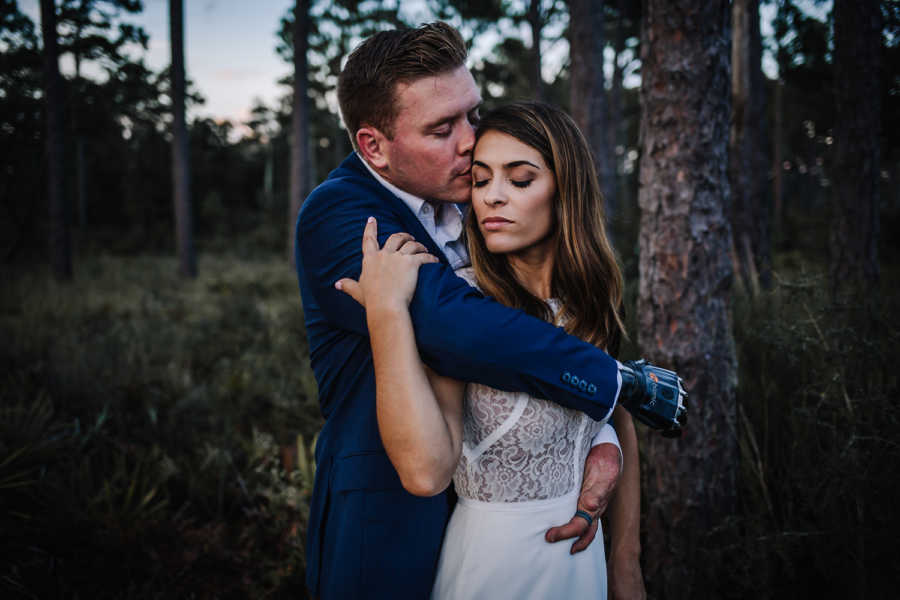 Groom kisses brides forehead and has arm wrapped around her