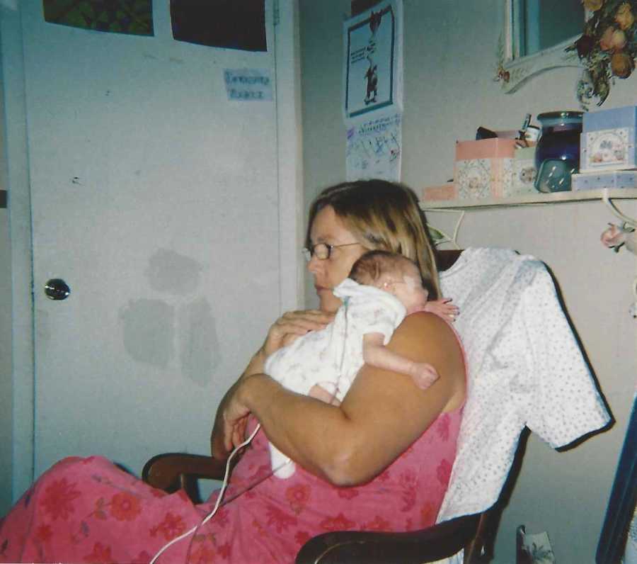 Grandmother sits in rocking chair holding newborn grandchild