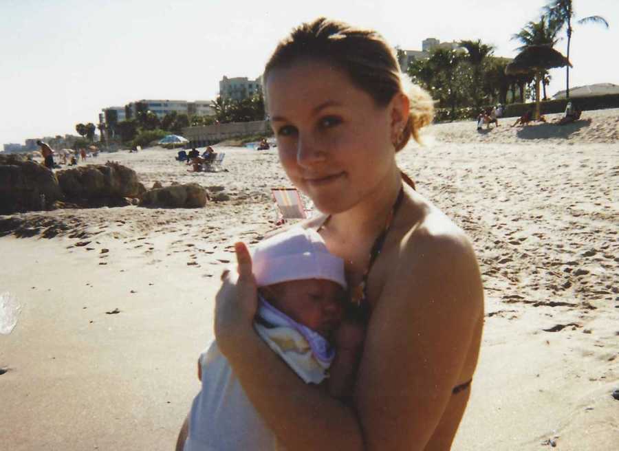 Teen mother holds baby daughter tight to her chest on beach