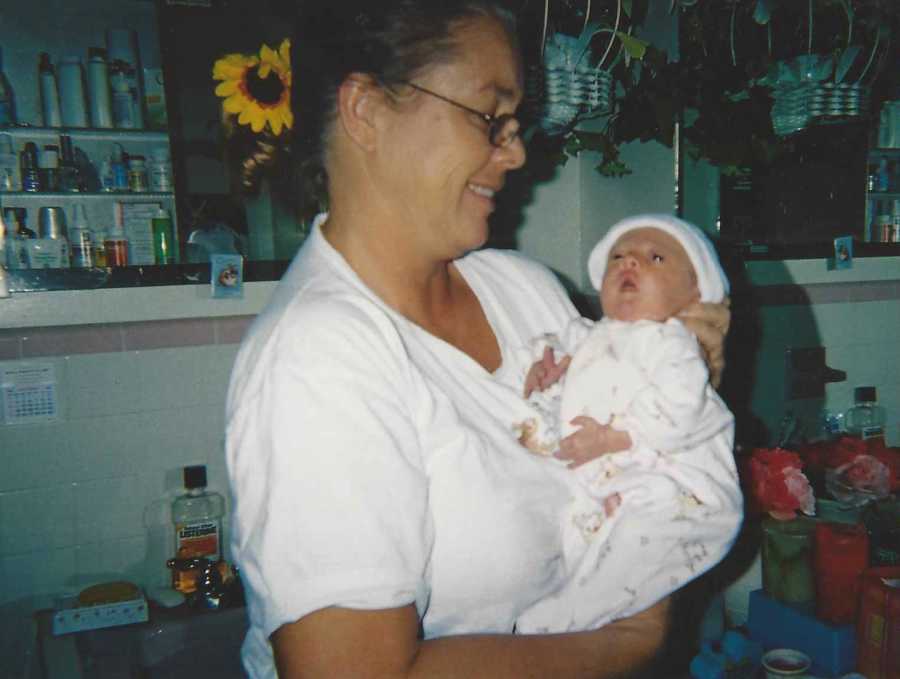 Woman smiling as she looks down at granddaughter in her arms