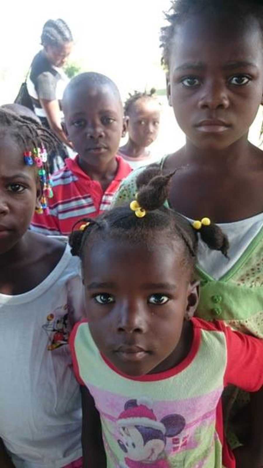 Faces of young Haitian orphans who all look sad