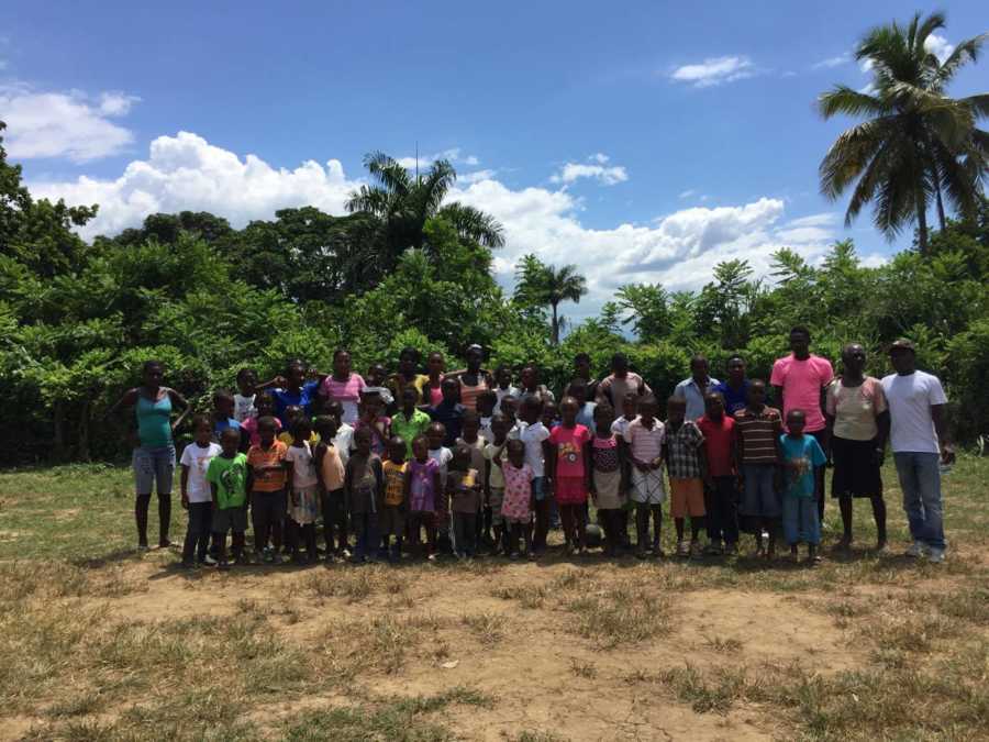 62 children man fosters in Haiti stands smiling outside