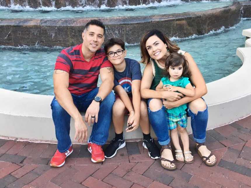 Woman who was sexually assaulted as a teen sits by fountain with husband and her two children