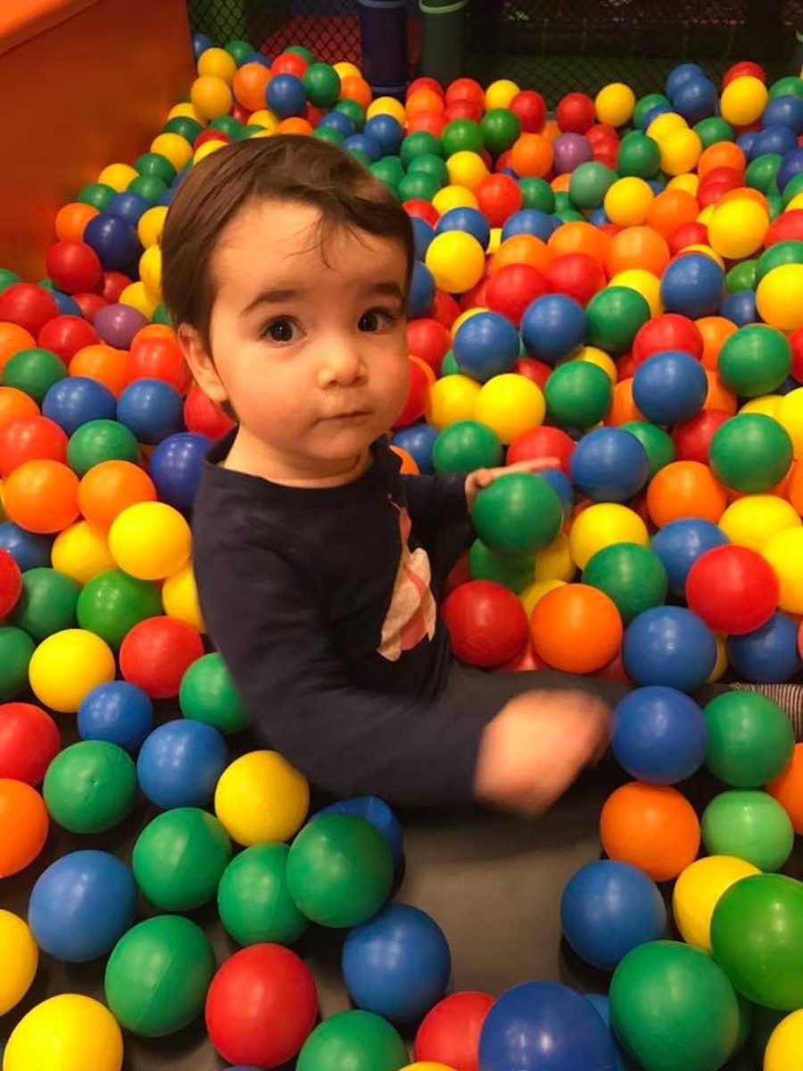 Little boy sitting in ball pit