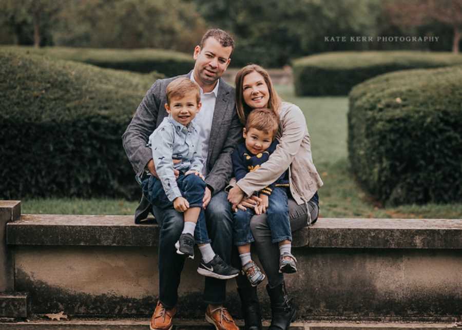 Woman who almost didn't live through child birth sits on ledge with husband and two sons