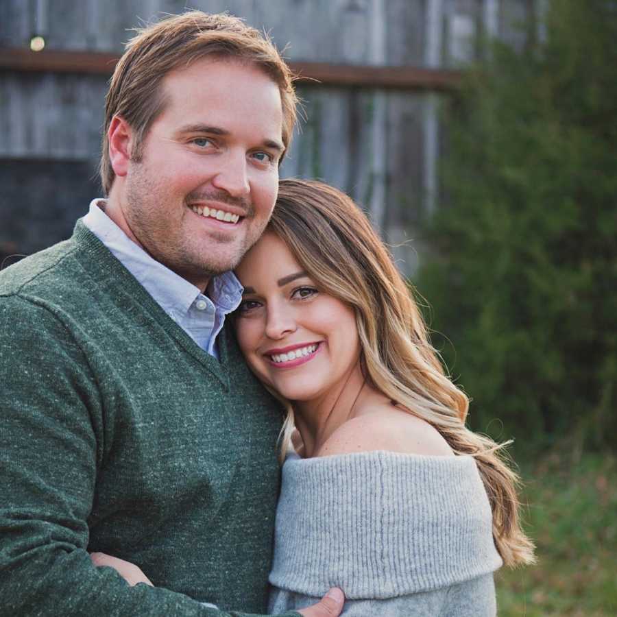 Husband and wife who lost their newborn hug and smile outside