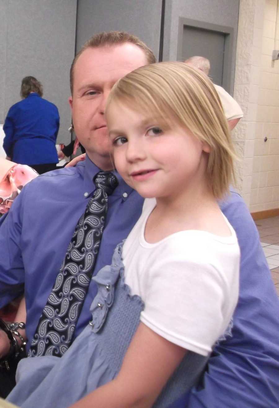 Man who has since passed from pancreatic cancer smiles as daughter sits on his lap