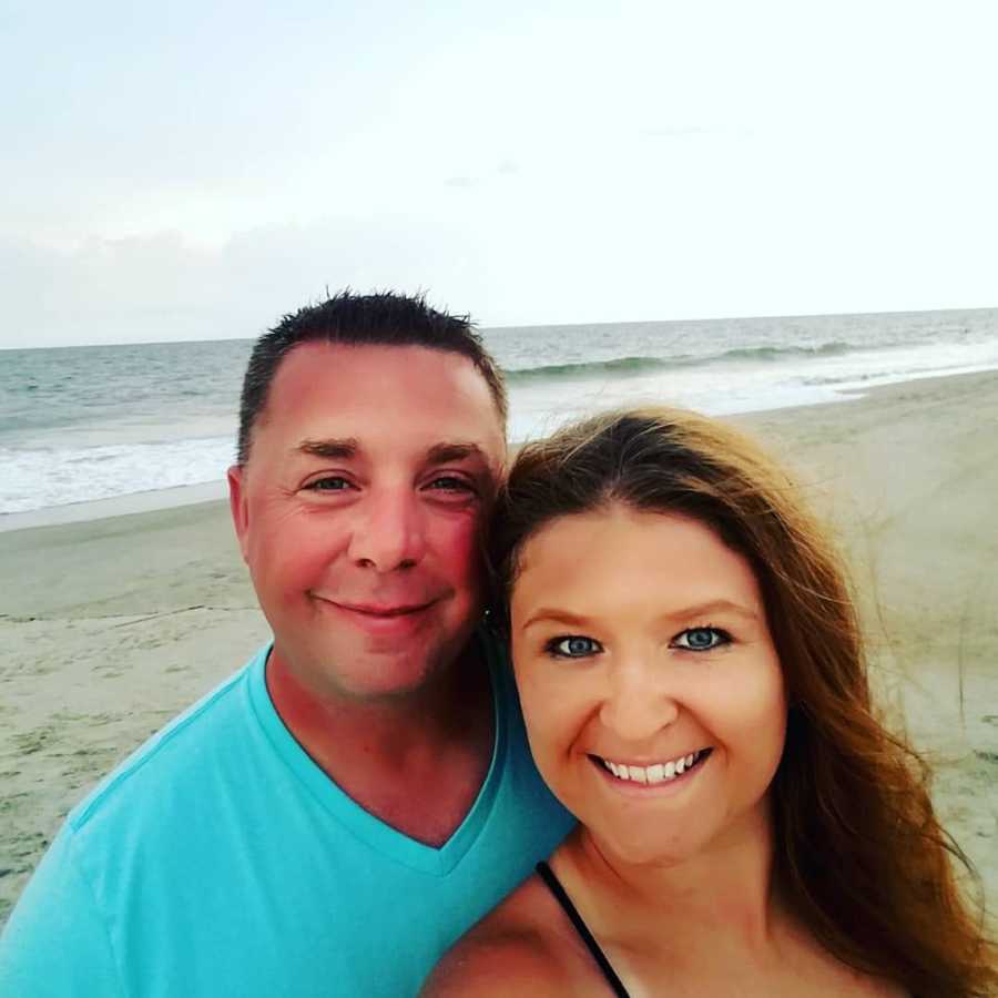 Woman smiles in selfie on beach with man who she found on online dating site