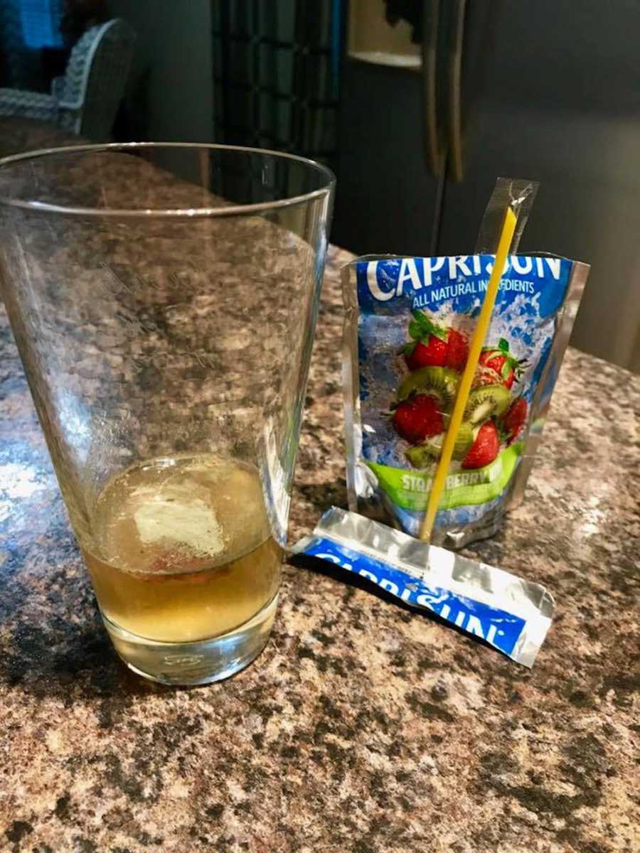 Class filled with Caprisun in glass with chunk of mold in it