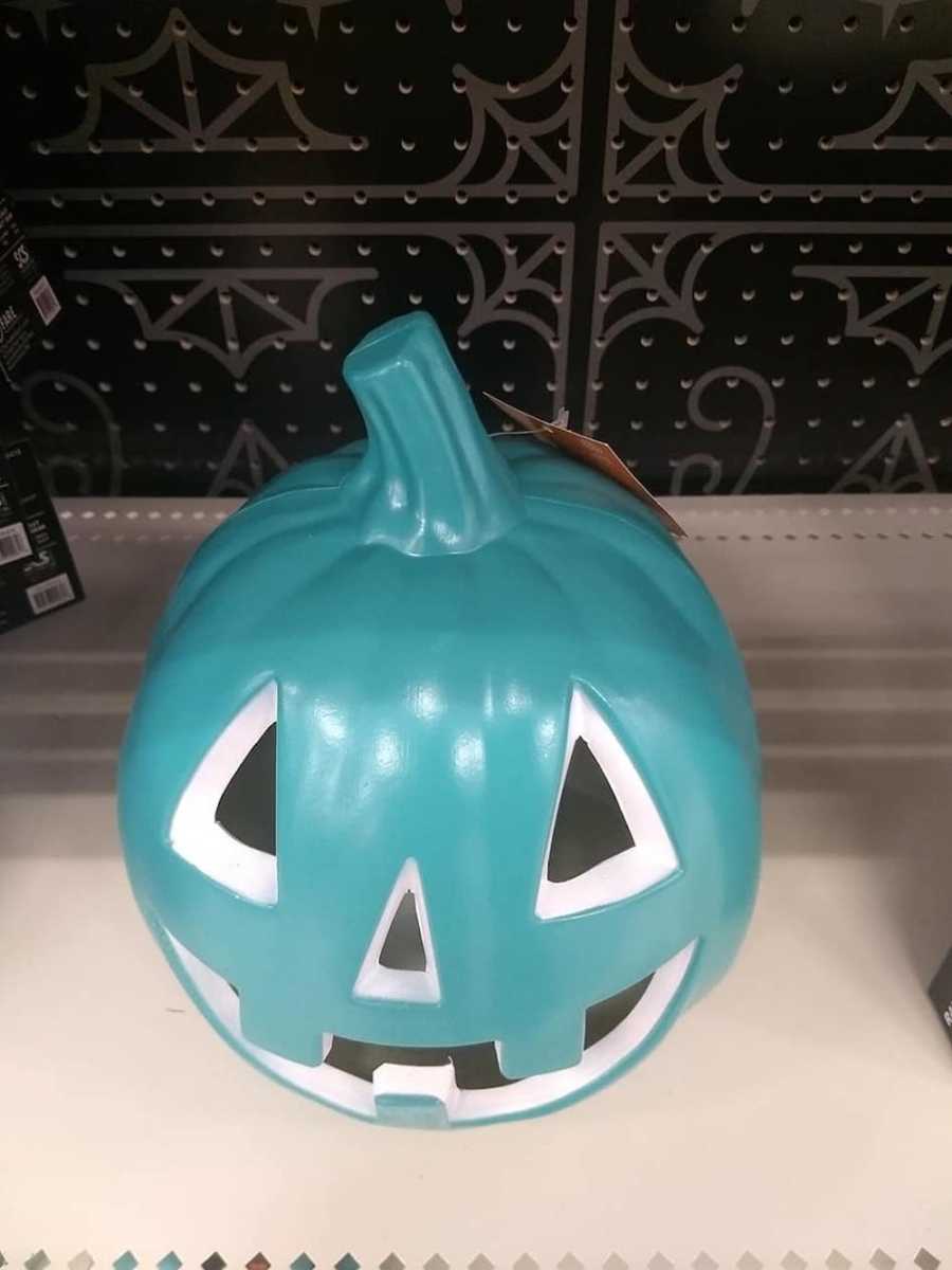 Teal jack-o-lantern sitting on shelf of store