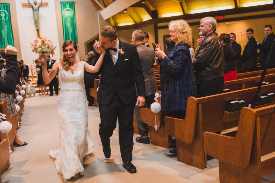 Groom kisses bride who says marriage isn't always perfect's hand as they walk down the aisle