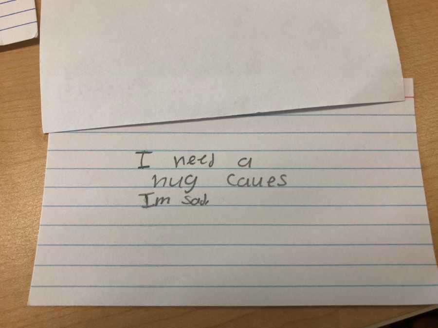Note card student wrote for teacher that says, "I need a hug cause I am sad"