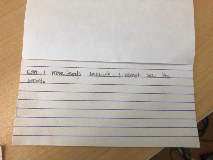 Note card student wrote for teacher that says, "can I move seats because I cannot see the board"
