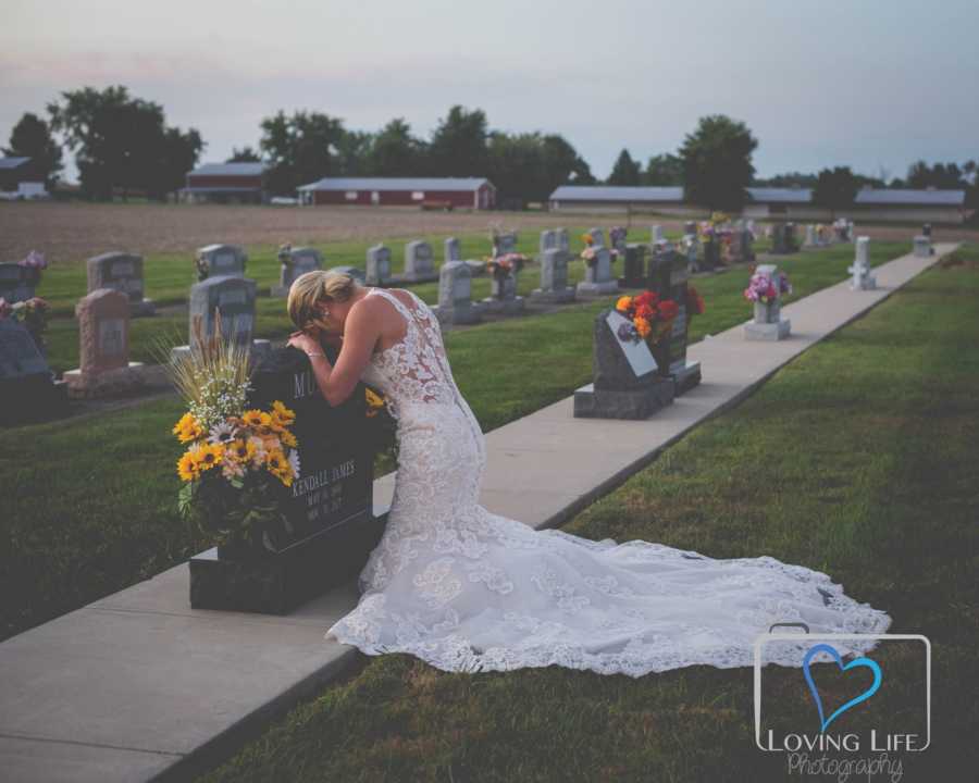 Woman in wedding gown leans over late fiancee's headstone 