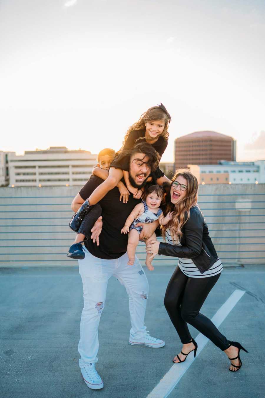 Woman stands beside boyfriend who is holding his son and her son and daughter