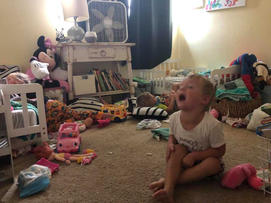 Little boy sits on floor of playroom screaming