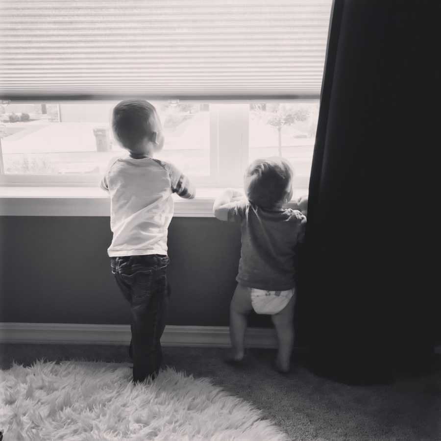 Two young boys stand looking out window of bedroom whose mother says she was meant to be a boy mom
