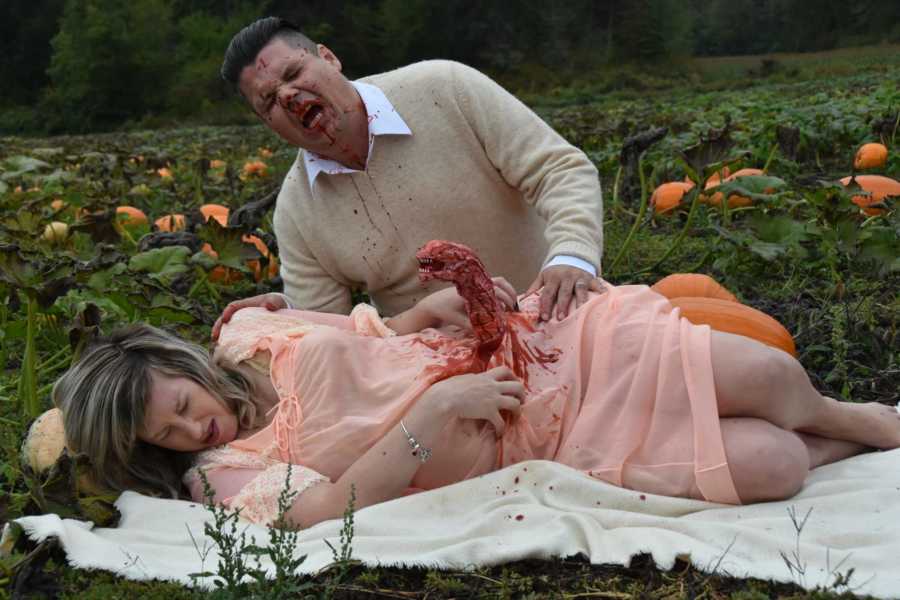 Pregnant woman lays on blanket in pumpkin patch while bloody monster comes out of her stomach and husband is covered in blood