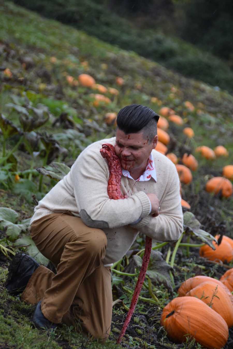 Man smiles as he hugs bloody creature that came out of his wife's stomach in pumpkin patch