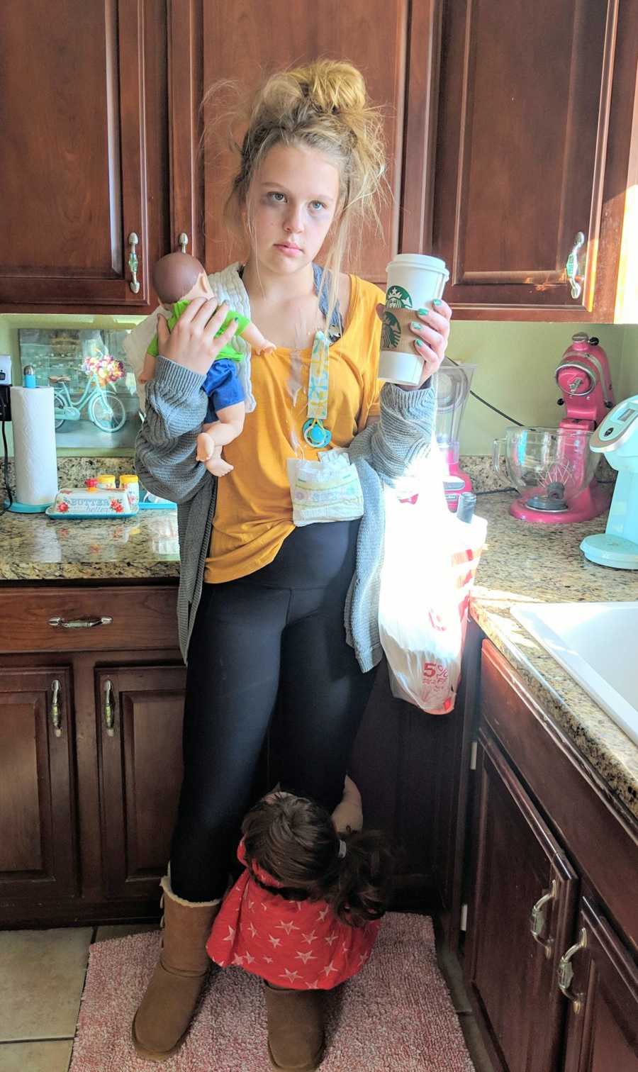 Teen dressed as "tired mom" stands in kitchen