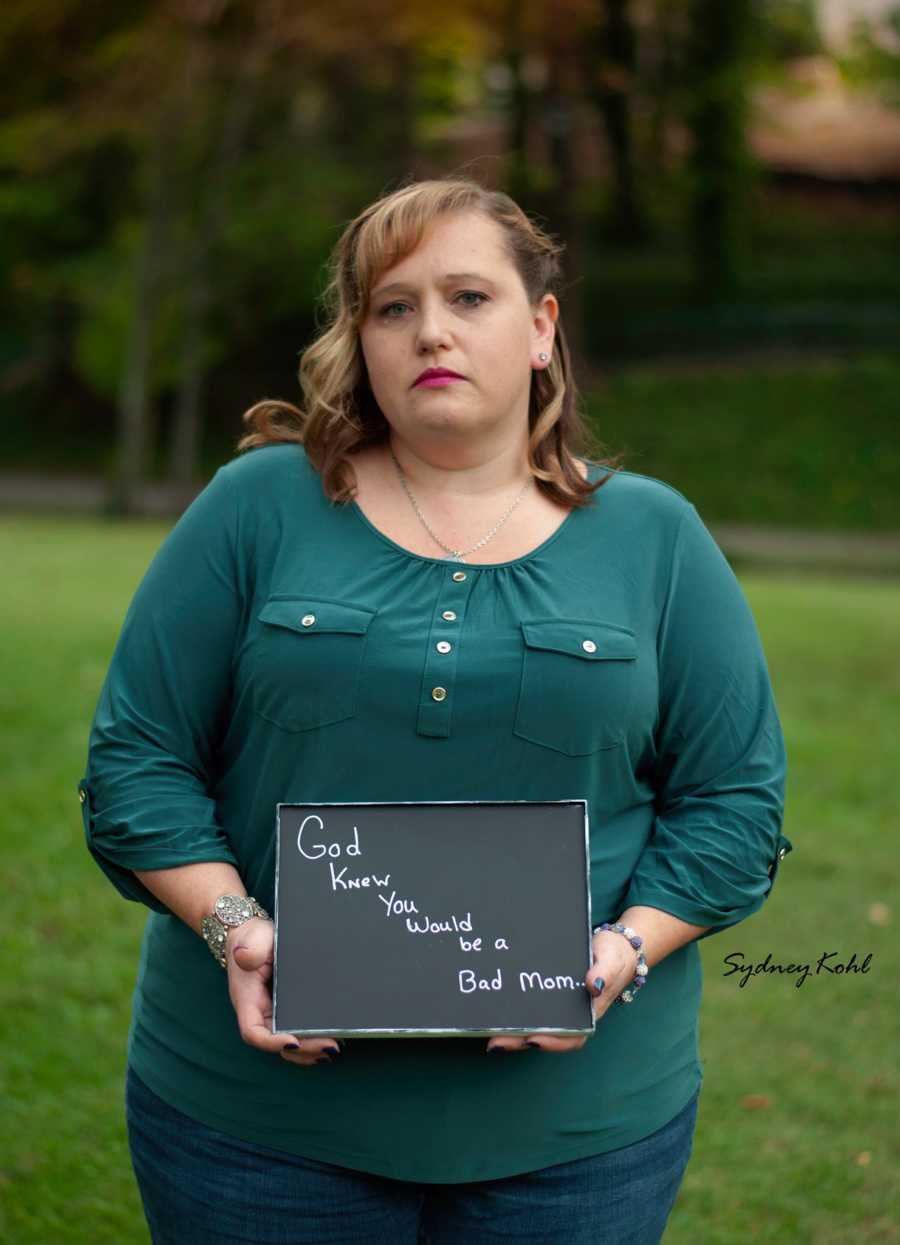 Woman who miscarried stands outside holding sign that says, "God knew you would be a bad mom"