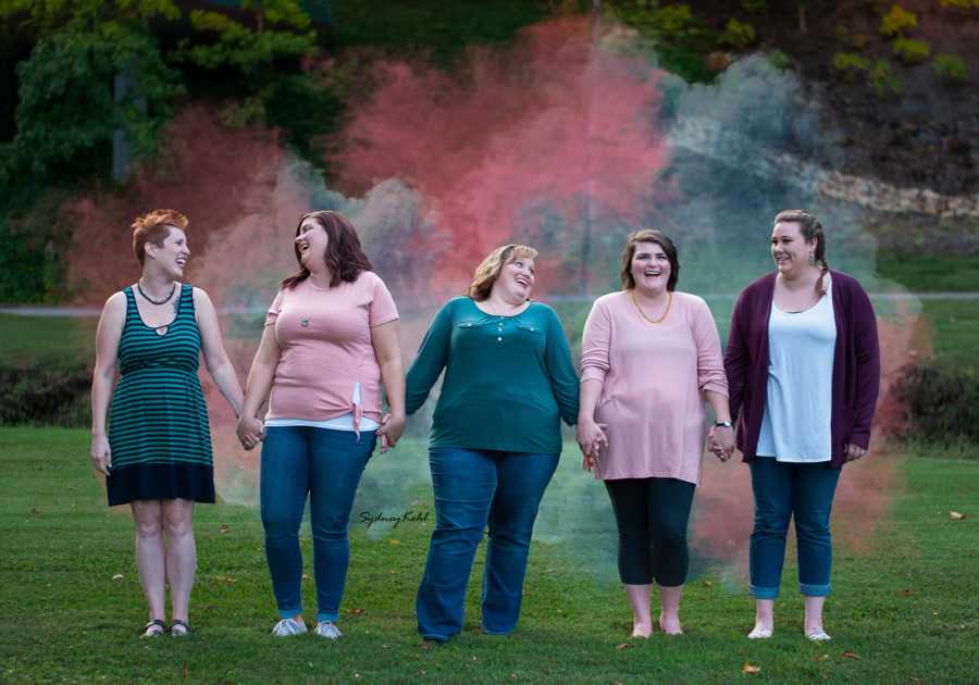 Woman stands outside holding hands with four other women who have experienced pregnancy loss