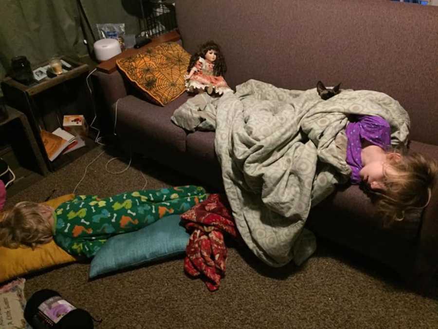 Child asleep on couch with doll sitting by his feet