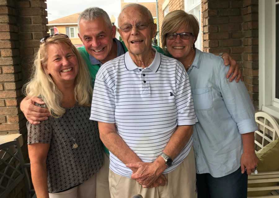 Man who was a foreign exchange student as a teen stands smiling with host and his two daughters