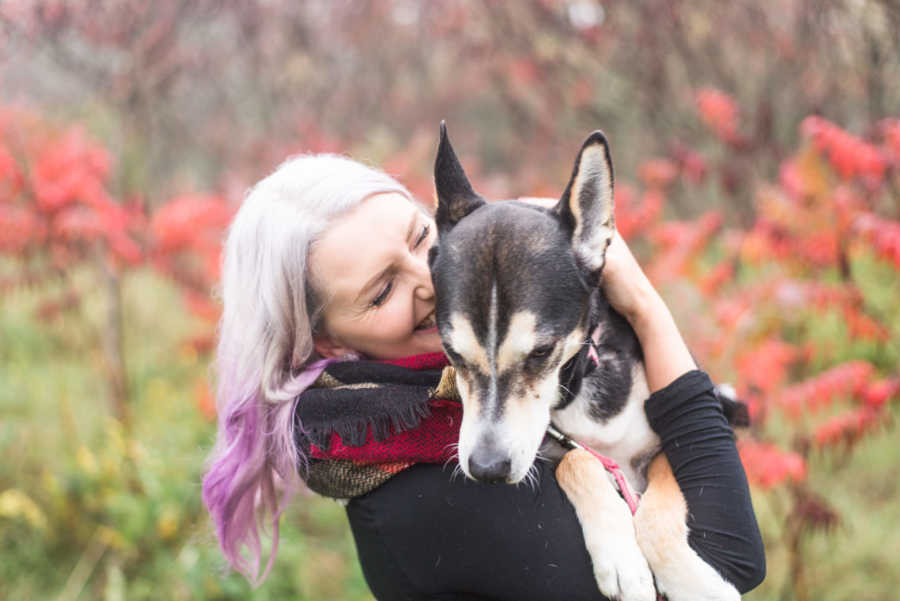 Woman smiles as she holds adopted dog in her arms 