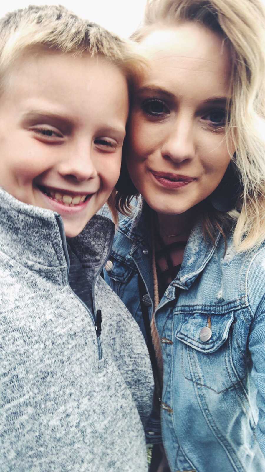 Young mom smiles in selfie beside her son