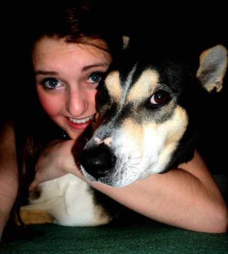 Young woman smiles while she wraps her arm around her adopted dog